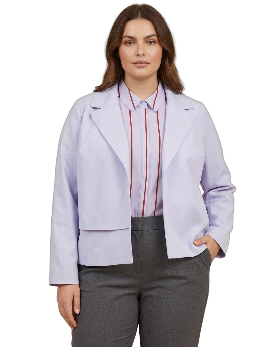 A woman modeling a light lavender cropped blazer over a pink striped button-down shirt and gray trousers, shot against a plain white background.