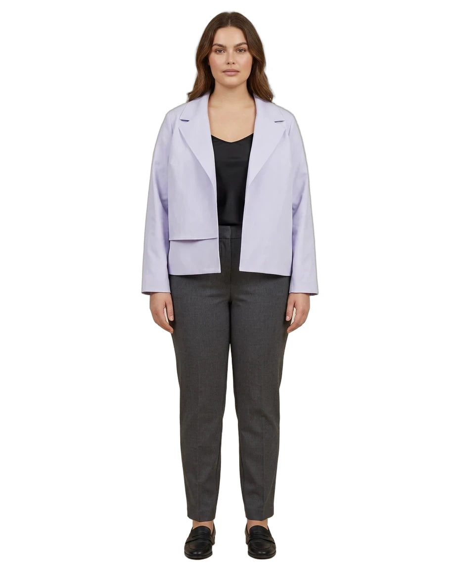 A woman modeling a light lavender blazer over a black top and dark gray trousers, standing against a plain white background.