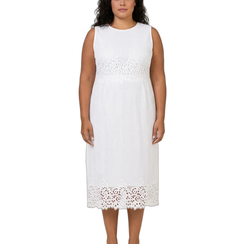 A woman modeling a sleeveless white midi dress with textured knit fabric and eyelet lace trim at the waist and hem, paired with white pointed-toe heels, against a plain white background.