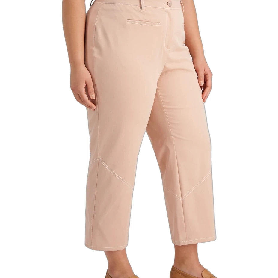 A model wearing a pair of cropped, straight-leg trousers in a light peach-beige color, styled with a navy blue top and tan loafers against a plain white background.