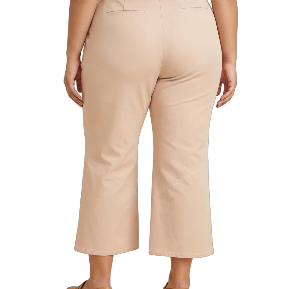 A person shown from the back wearing light beige cropped pants and tan flats against a plain white studio background.