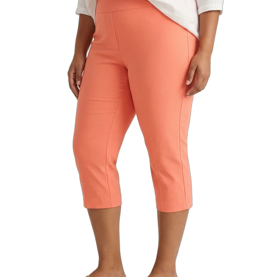 A model wearing coral orange capri pants, a white top, and tan slide sandals, shown from the waist down against a plain white background.