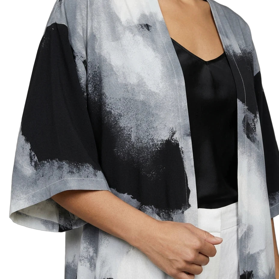 Person wearing a black and white abstract patterned kimono over a black top and white pants.