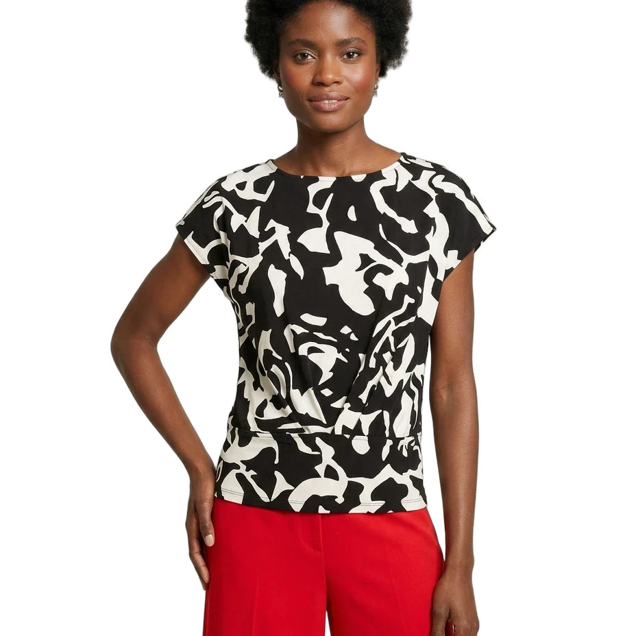 Woman wearing a black and white patterned top with red pants on a white background
