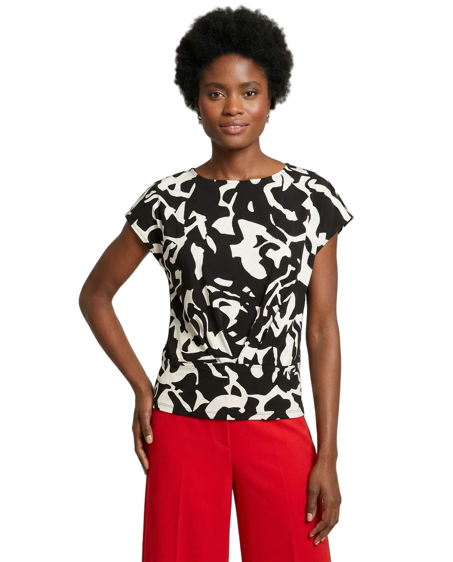 Woman wearing a black and white patterned top with red pants on a white background
