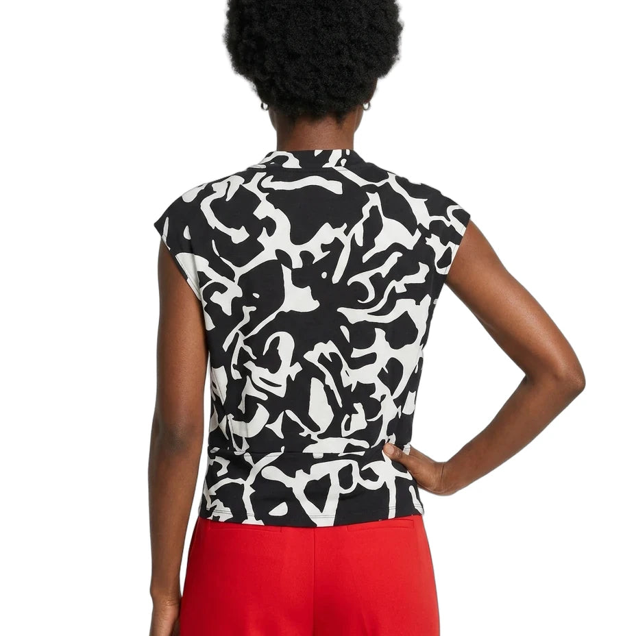 Person wearing a black and white patterned top with red pants on a white background