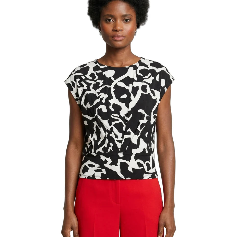 Woman wearing a black and white patterned top with red pants on a white background
