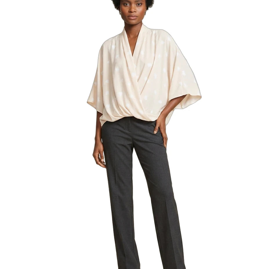 A model wearing a cream-colored, draped short-sleeve top and dark charcoal gray straight-leg trousers, paired with brown strappy heels, against a plain white background.