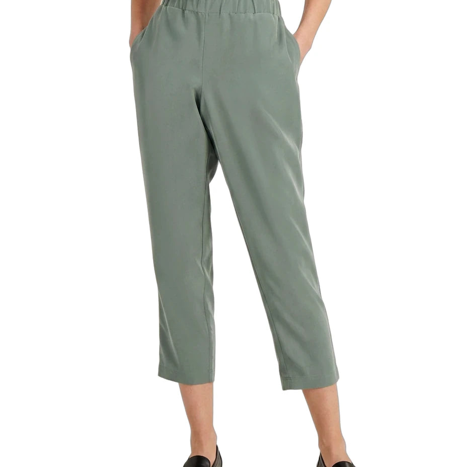A model wearing sage green cropped pants with an elastic waistband, paired with a white top and black loafers, shown from the waist down on a white background.