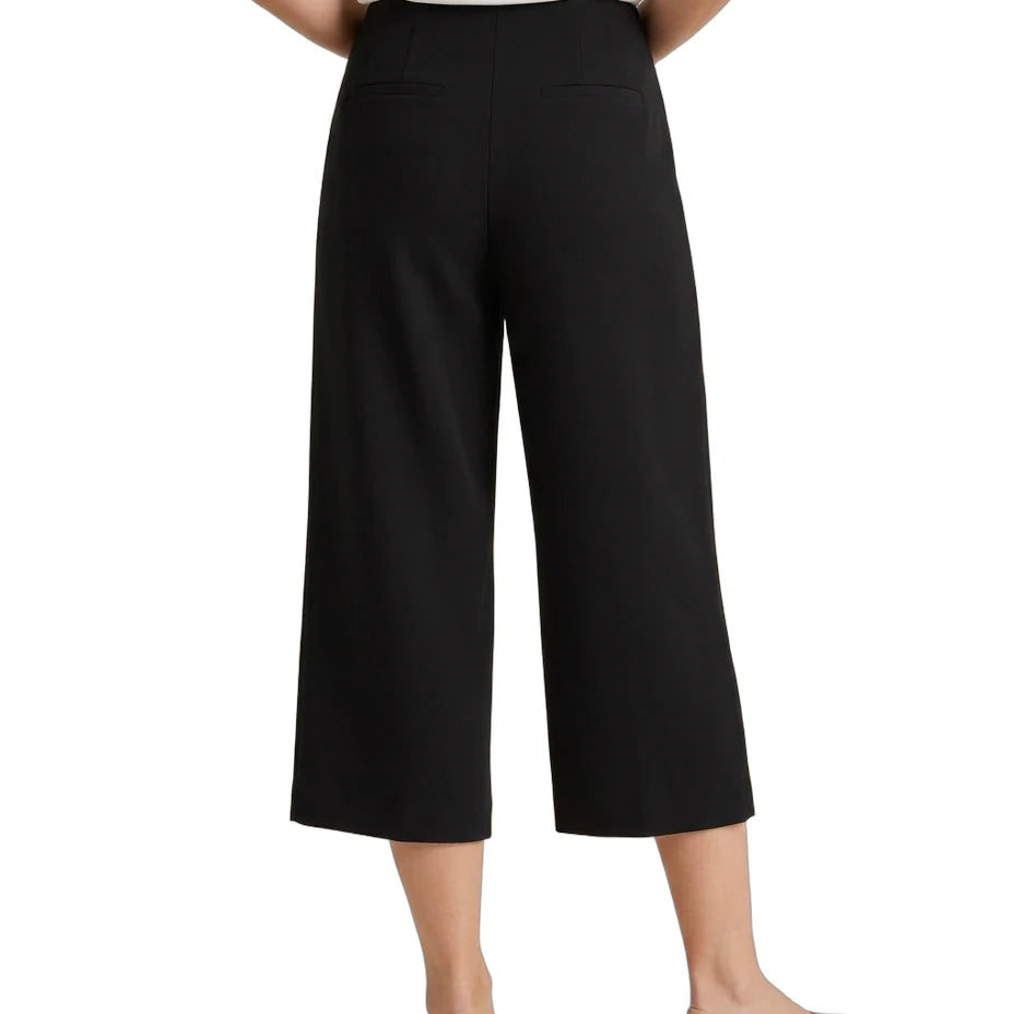 A model shown from the back wearing black cropped wide-leg pants, a white top, and beige flats against a plain white background.
