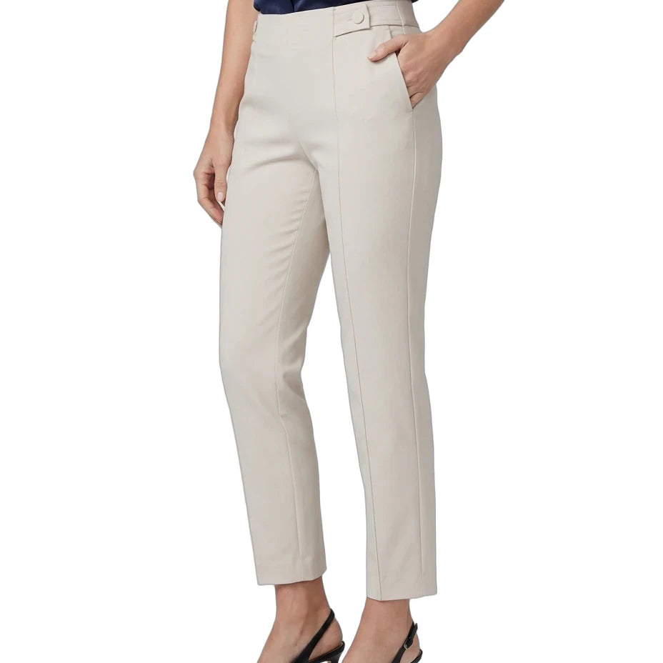 A model wearing high-waisted, straight-leg cropped trousers in a light beige color, paired with a navy blue top and black slingback heels, shown against a plain white background.