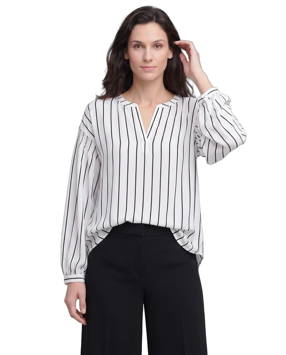 Woman wearing a black and white striped blouse with black pants on a white background