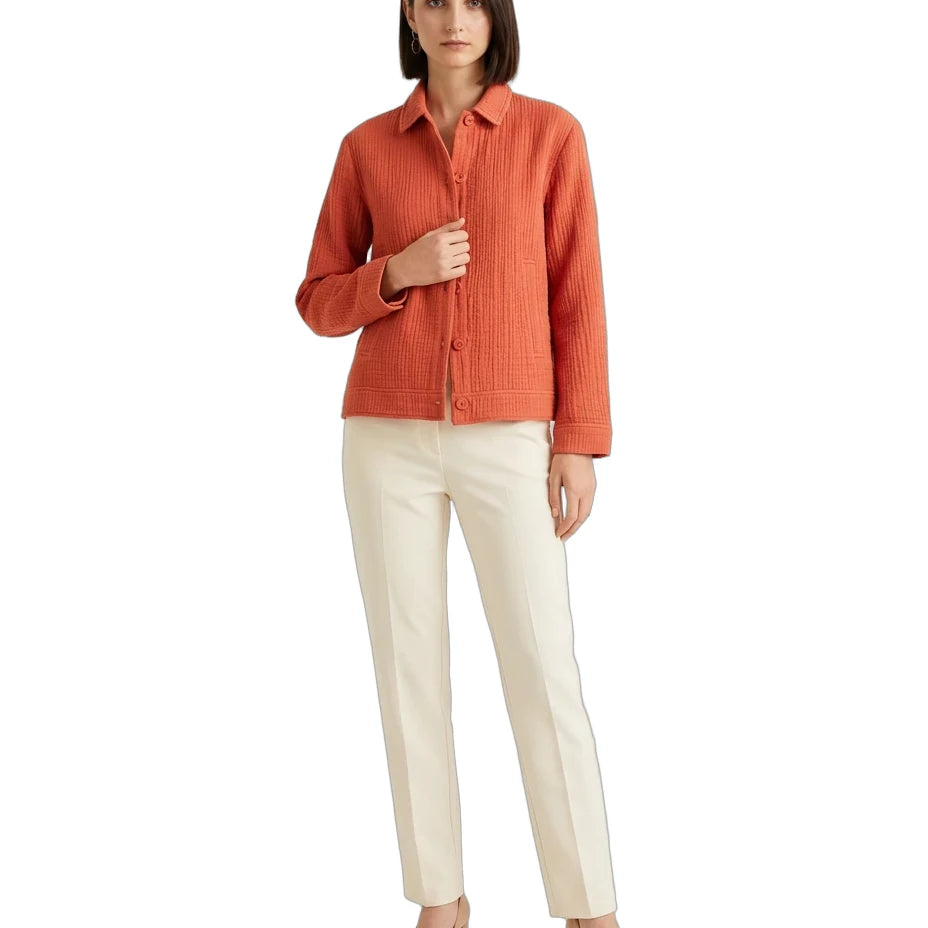A woman modeling a textured orange button-up shirt paired with off-white trousers and beige heels, set against a plain white background.