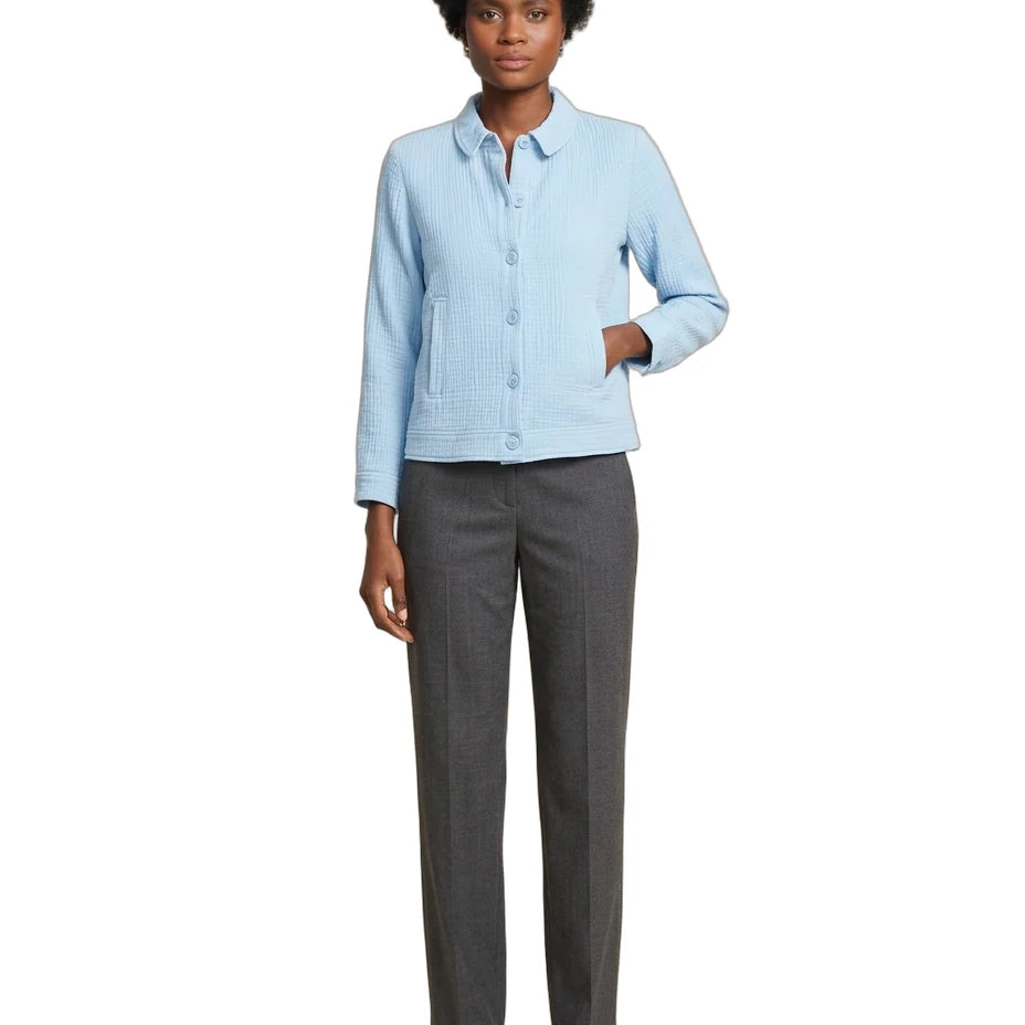 A woman modeling a light blue textured long-sleeve button-up shirt paired with dark gray straight-leg trousers and brown strappy sandals, set against a plain white background.