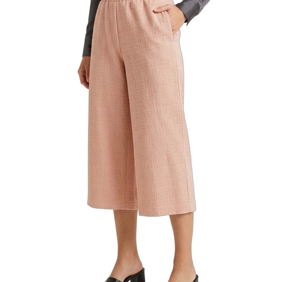 A model wearing a pair of high-waisted, wide-leg cropped pants in a textured dusty pink fabric, paired with a dark gray long-sleeve top and black block-heel slide sandals, set against a plain white background.