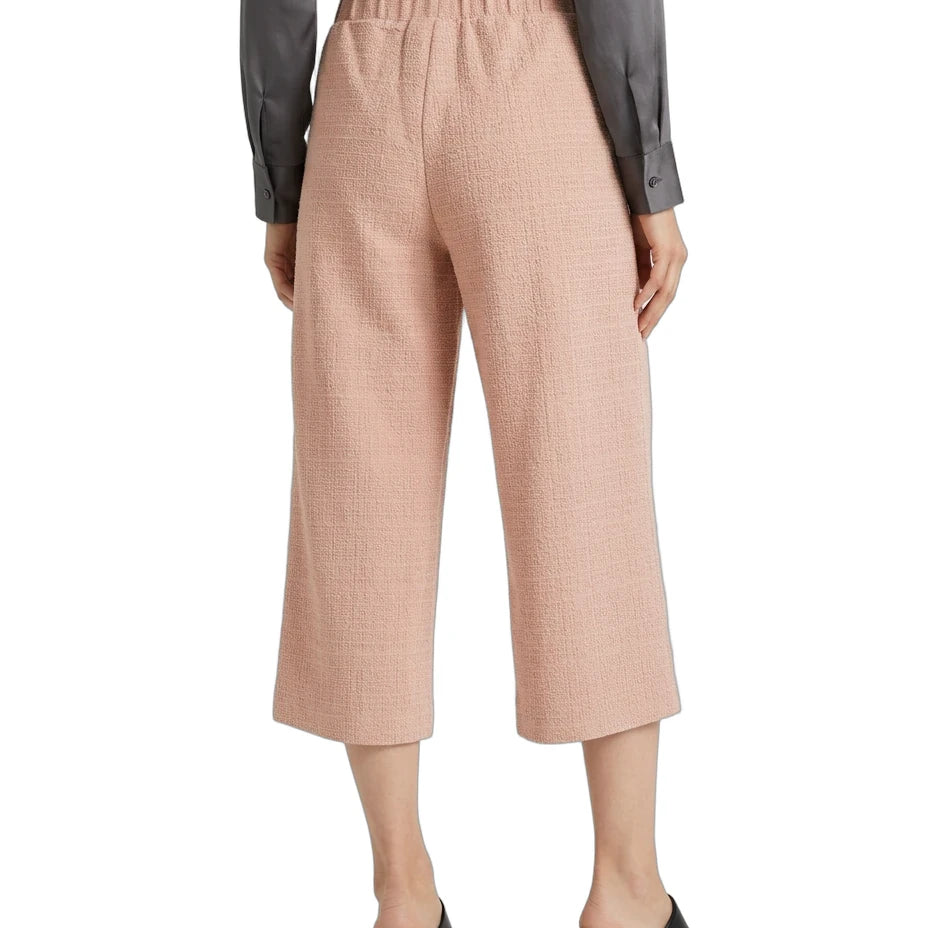 A model is shown from the back wearing high-waisted, cropped wide-leg trousers in a dusty rose pink color, paired with a dark gray long-sleeve shirt and black block-heel slide sandals, against a plain white background.
