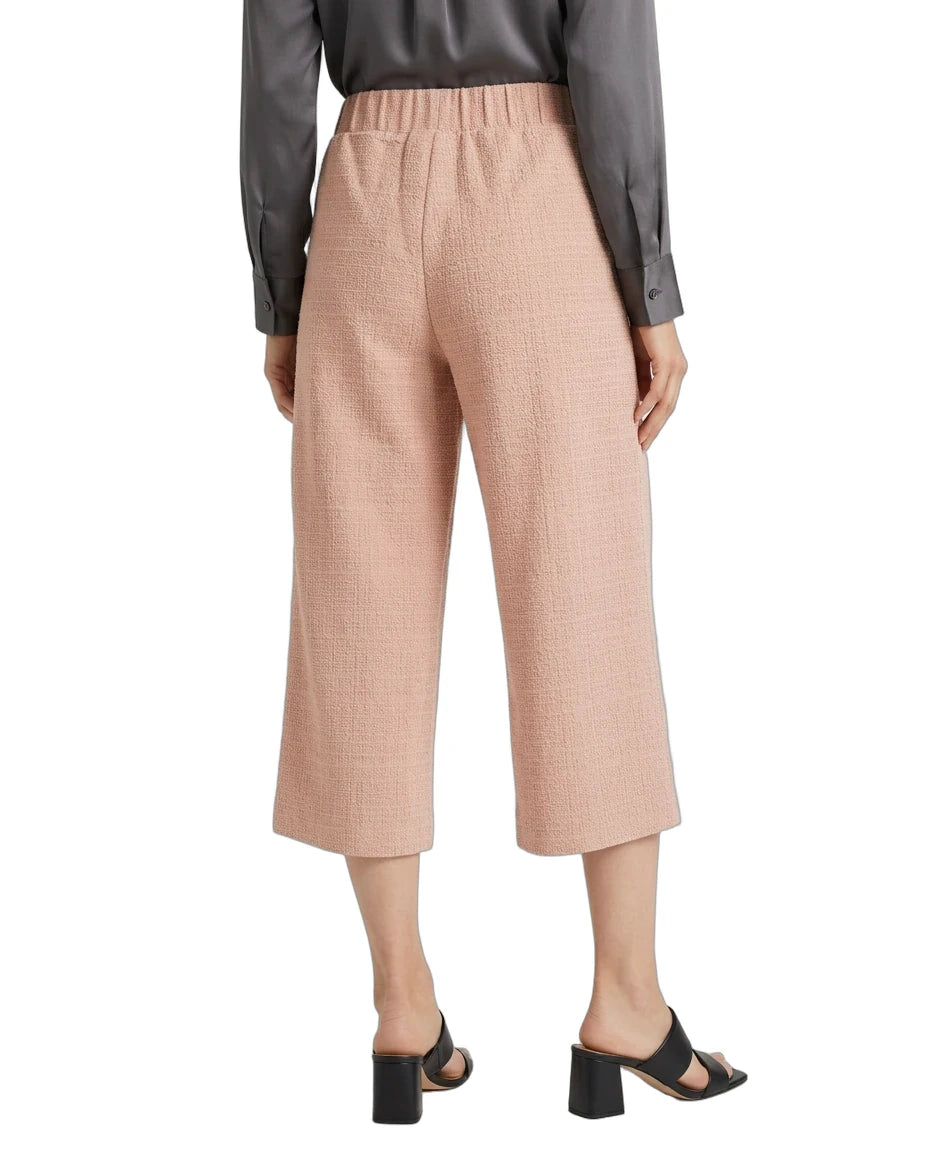 A model is shown from the back wearing high-waisted, cropped wide-leg trousers in a dusty rose pink color, paired with a dark gray long-sleeve shirt and black block-heel slide sandals, against a plain white background.