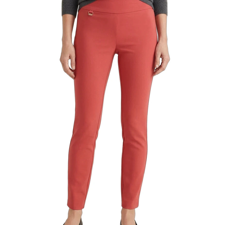 A model from the waist down wearing slim-fit coral red ankle-length pants, a dark gray long-sleeve top, and black flats, against a plain white background.