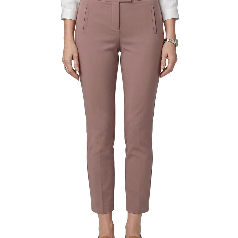 A model wearing slim-fit, ankle-length trousers in a dusty rose pink color, paired with a white long-sleeve blouse and brown leather loafers, shown against a plain white background.