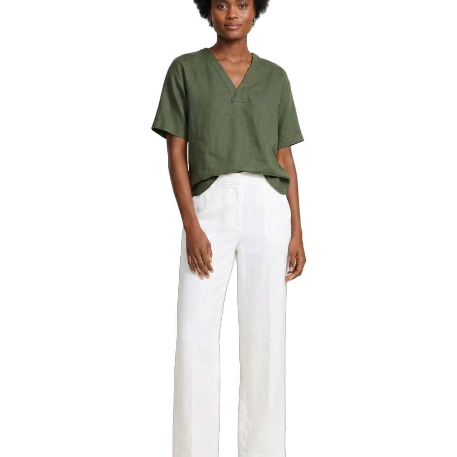 A woman modeling a short-sleeve olive green V-neck top and white wide-leg pants with black sandals, photographed against a plain white background.