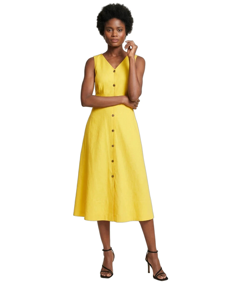 A woman modeling a sleeveless yellow midi dress with a V-neckline and a front button placket, paired with black strappy high-heeled sandals, set against a plain white background.