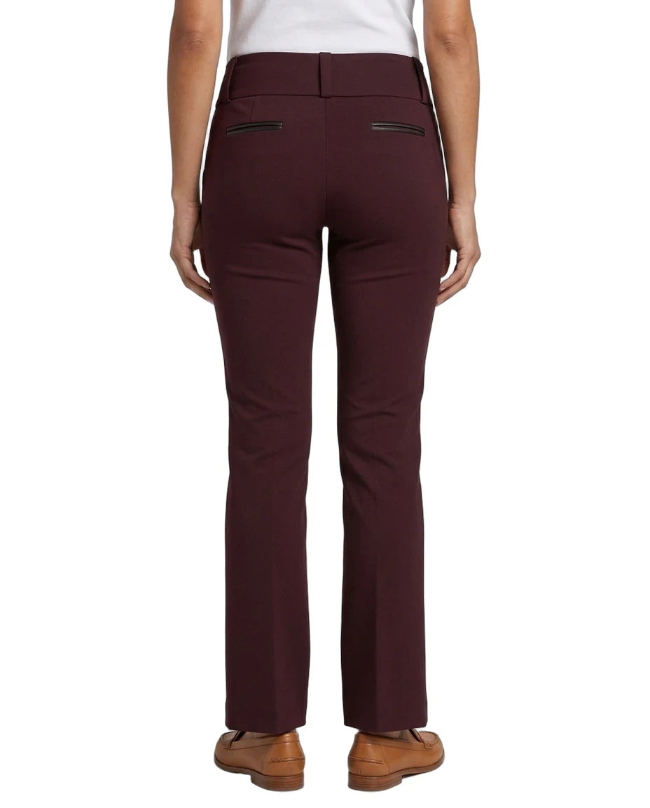 Rear view of a model wearing high-waisted, straight-leg trousers in a deep burgundy color, paired with a white top and brown shoes, against a plain white background.