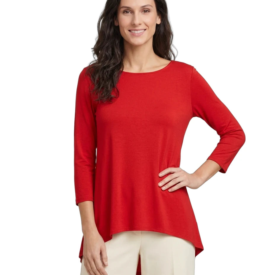 A woman modeling a bright red three-quarter sleeve top with a high-low hem, paired with cream pants, against a plain white background.
