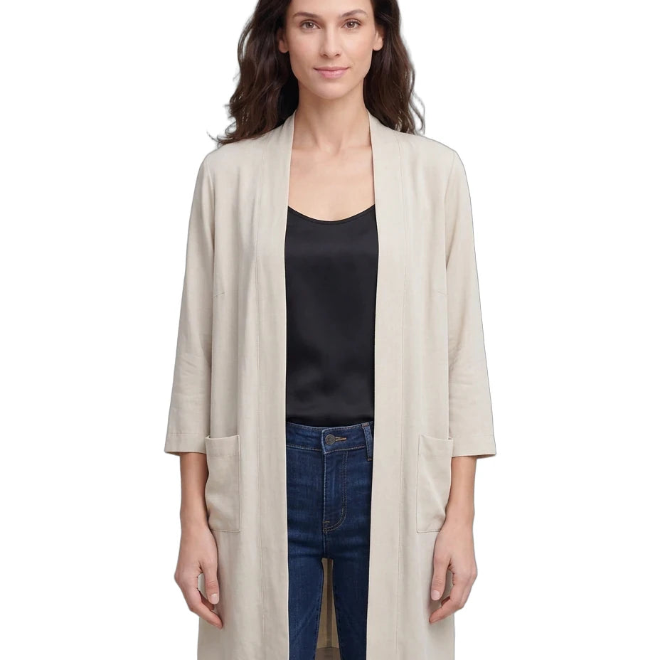 Woman wearing a beige cardigan over a black top and blue jeans on a white background