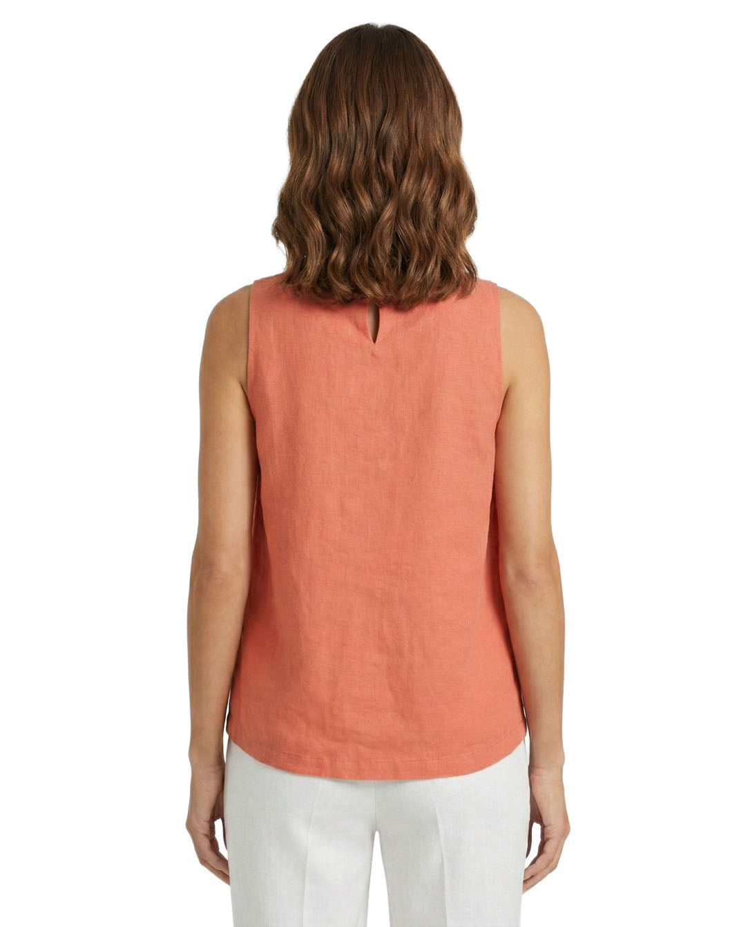 Woman wearing a coral sleeveless top and white pants on a white background