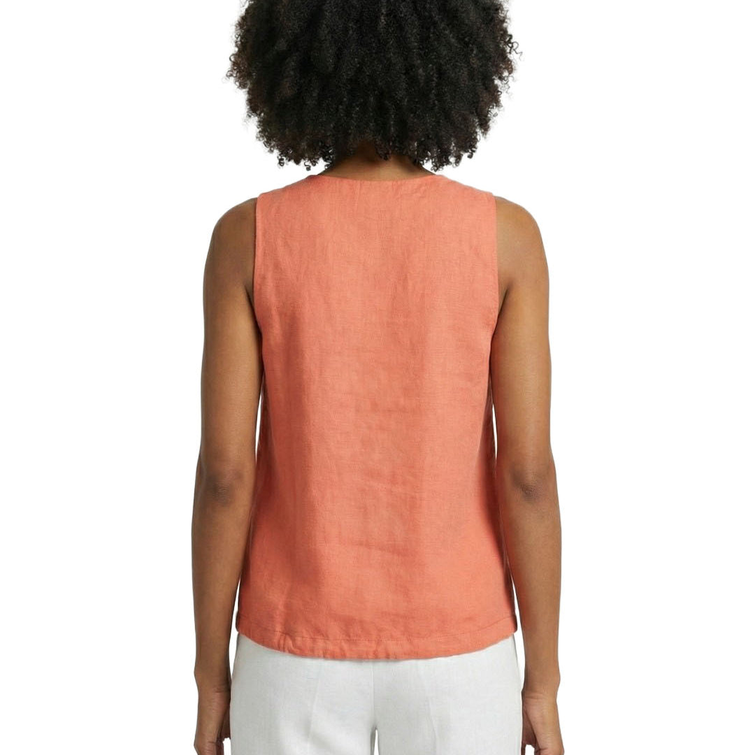 Person wearing a coral sleeveless top and white pants on a white background