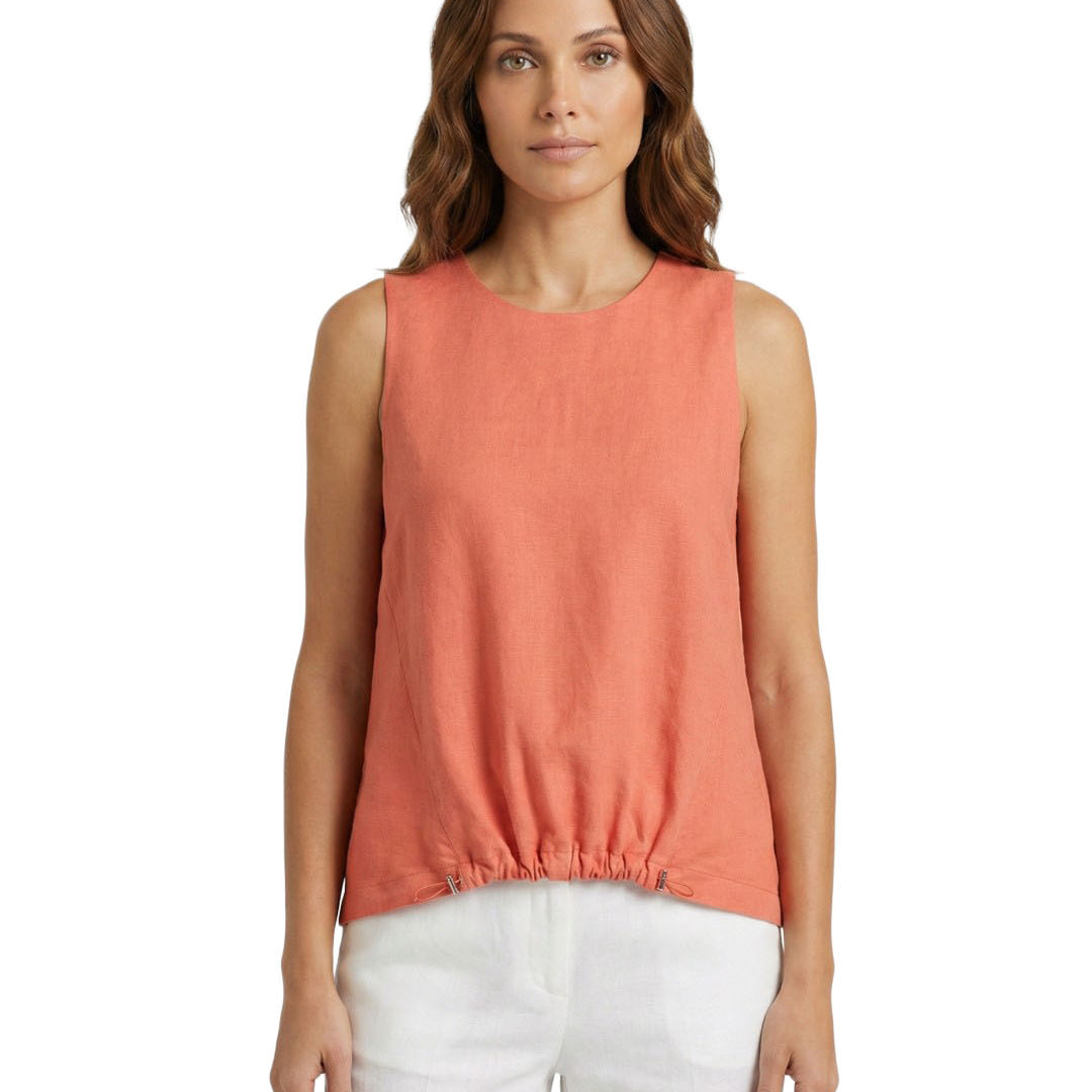 Woman wearing a coral sleeveless top and white pants on a white background