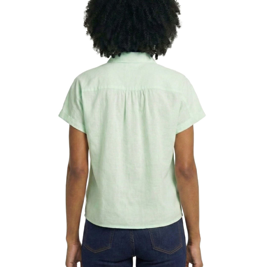 Person wearing a light green shirt and dark blue jeans on a white background