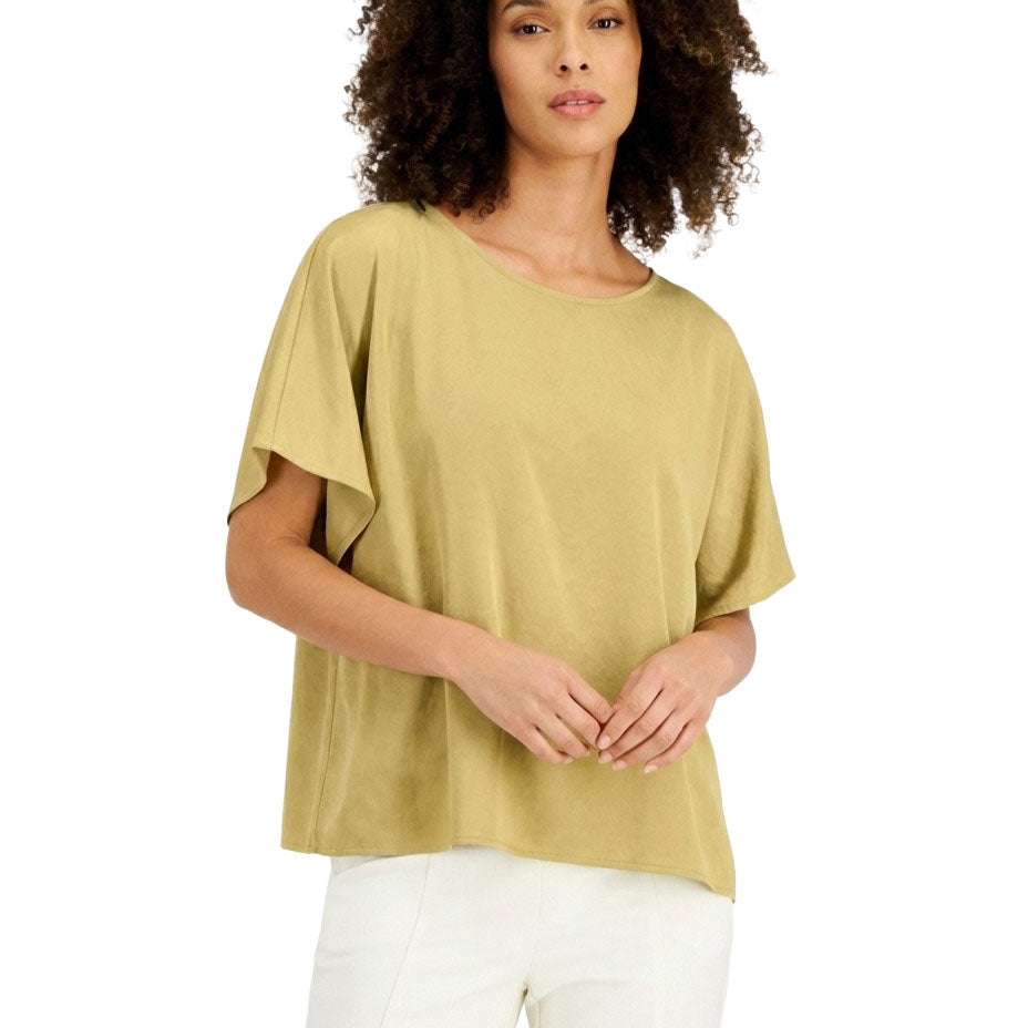 Woman wearing a green top and white pants on a white background