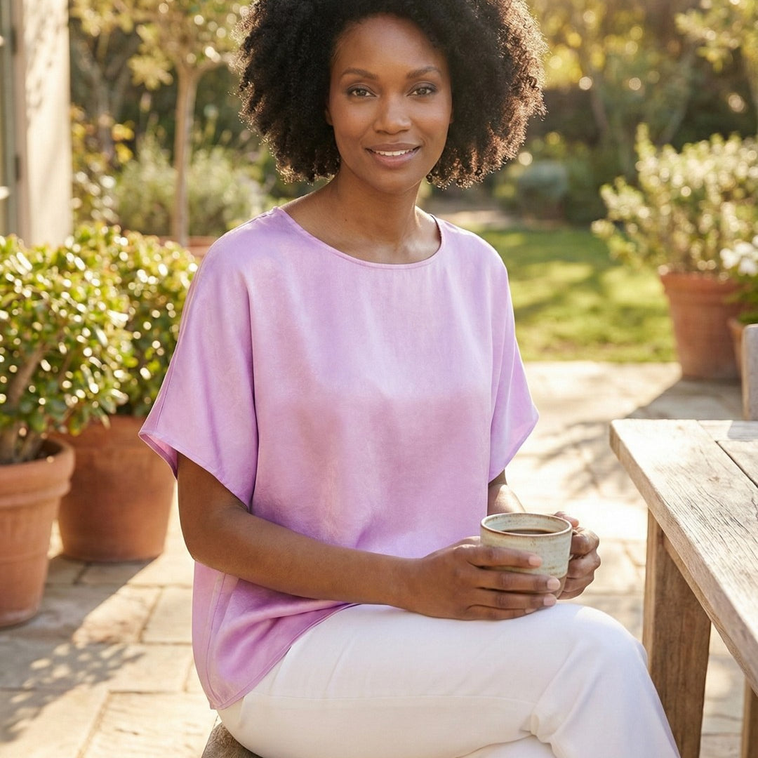 Woman in a pink shirt holding a cup outdoors