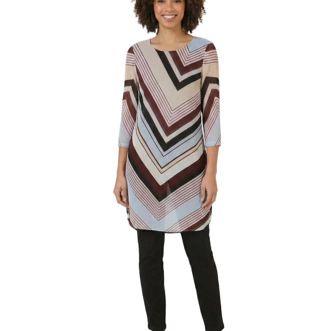 Woman wearing a patterned tunic over black pants on a white background