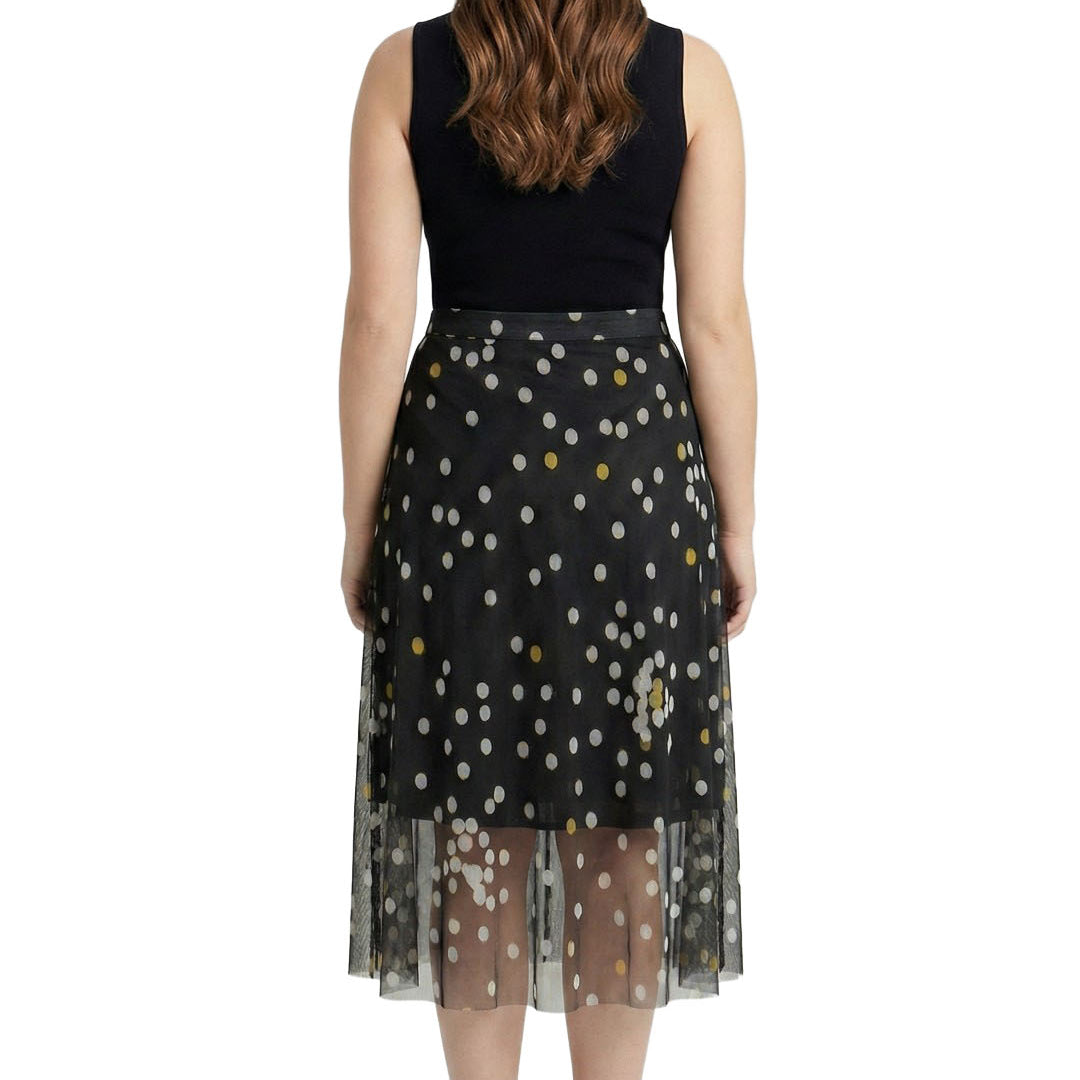 Woman wearing a black sleeveless top and a black skirt with white polka dots on a white background
