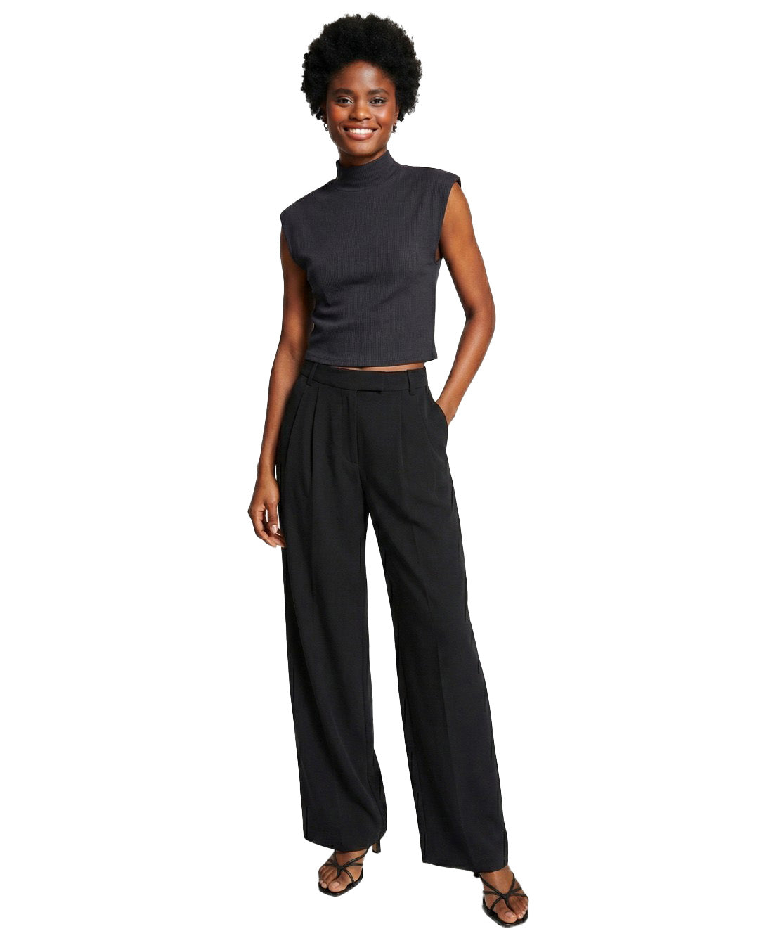 Woman wearing a black sleeveless top and wide-leg pants on a white background