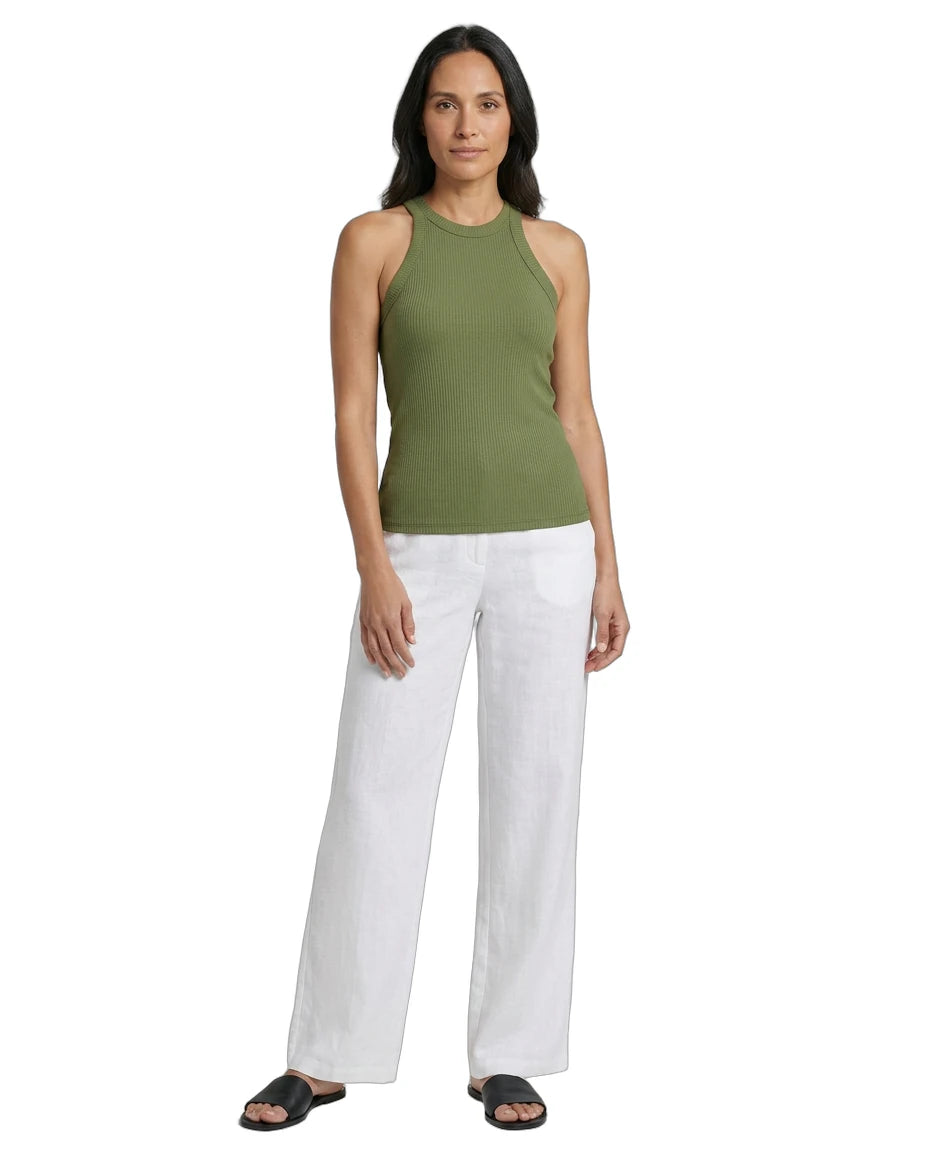 Woman wearing a green sleeveless top and white pants on a white background
