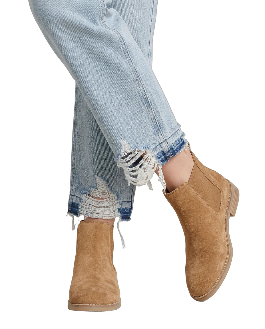 Tan ankle boots worn with light blue jeans on a white background