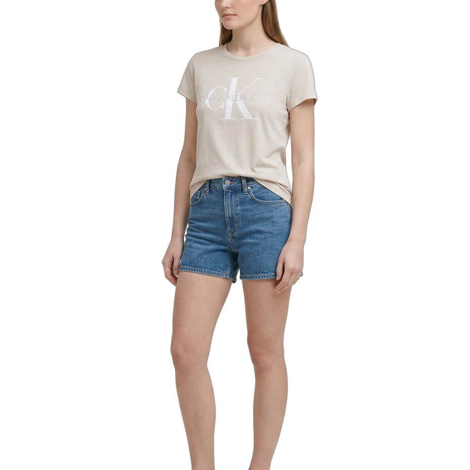 Woman wearing a beige Calvin Klein t-shirt and blue denim shorts on a white background