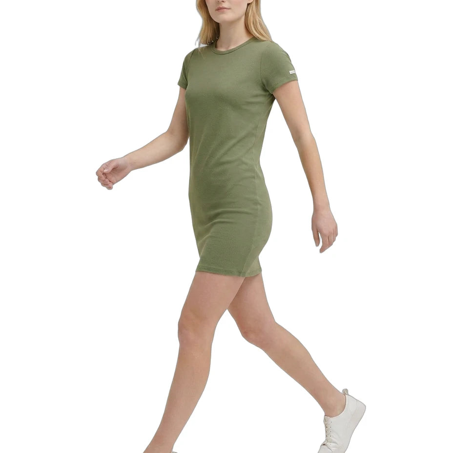 Woman wearing a green Calvin Klein dress and white sneakers on a white background