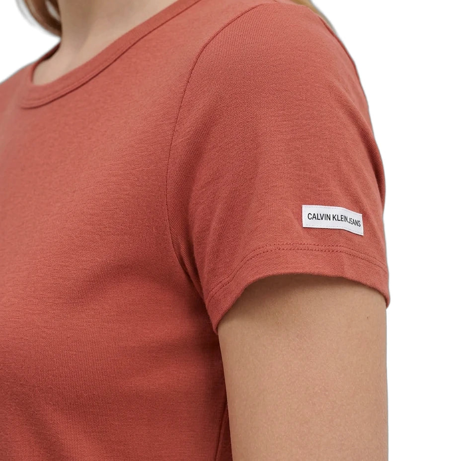 Person wearing a red t-shirt with a Calvin Klein label on a white background