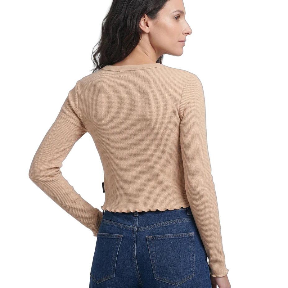 Woman wearing a beige long-sleeve top and blue jeans on a white background