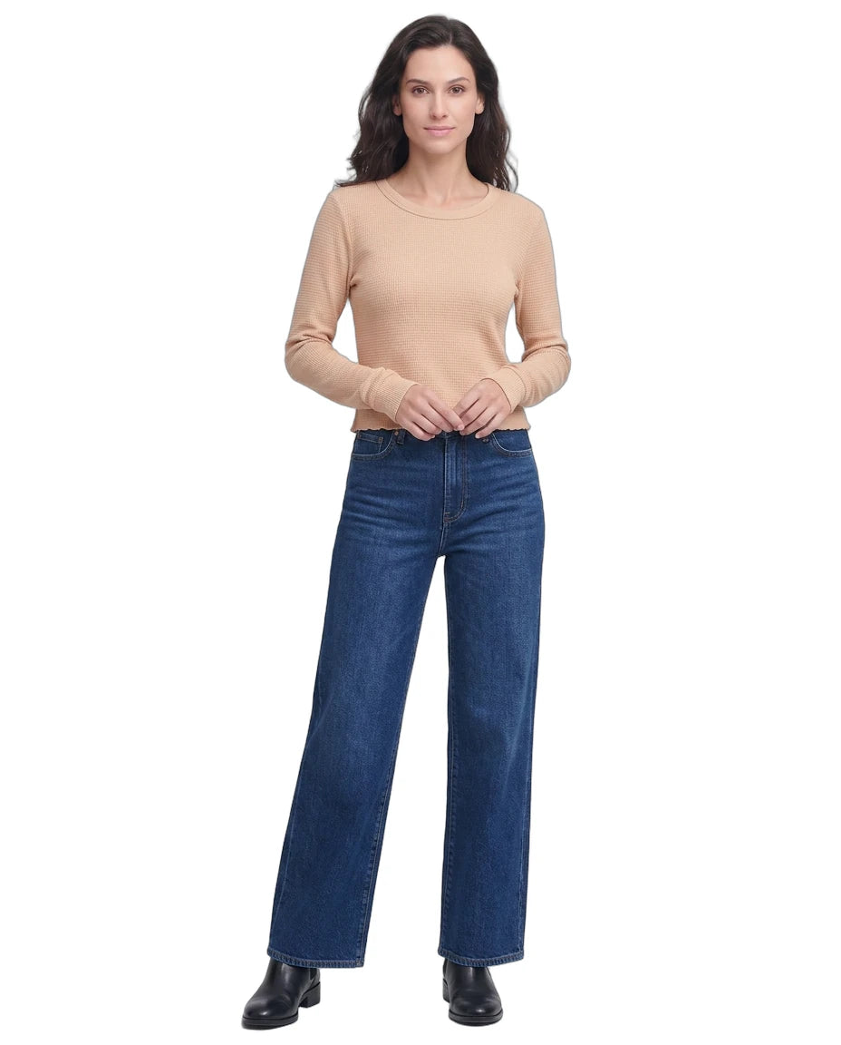Woman wearing a beige sweater and blue jeans on a white background
