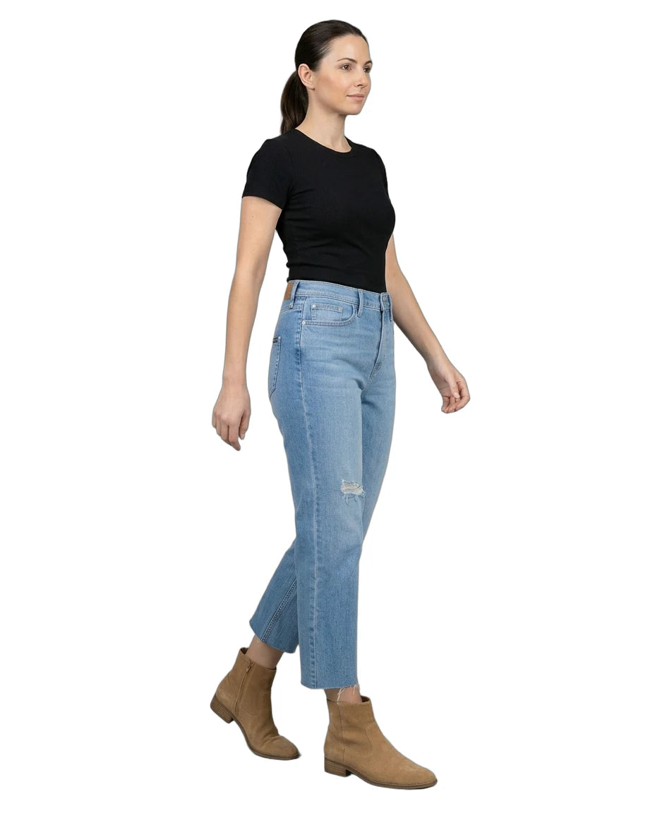 Woman wearing light blue jeans and a black top on a white background