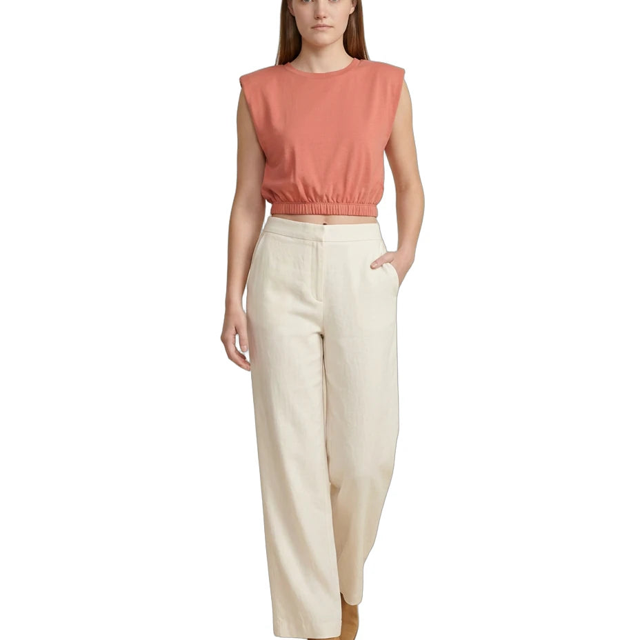 Woman wearing a coral sleeveless top and beige pants on a white background