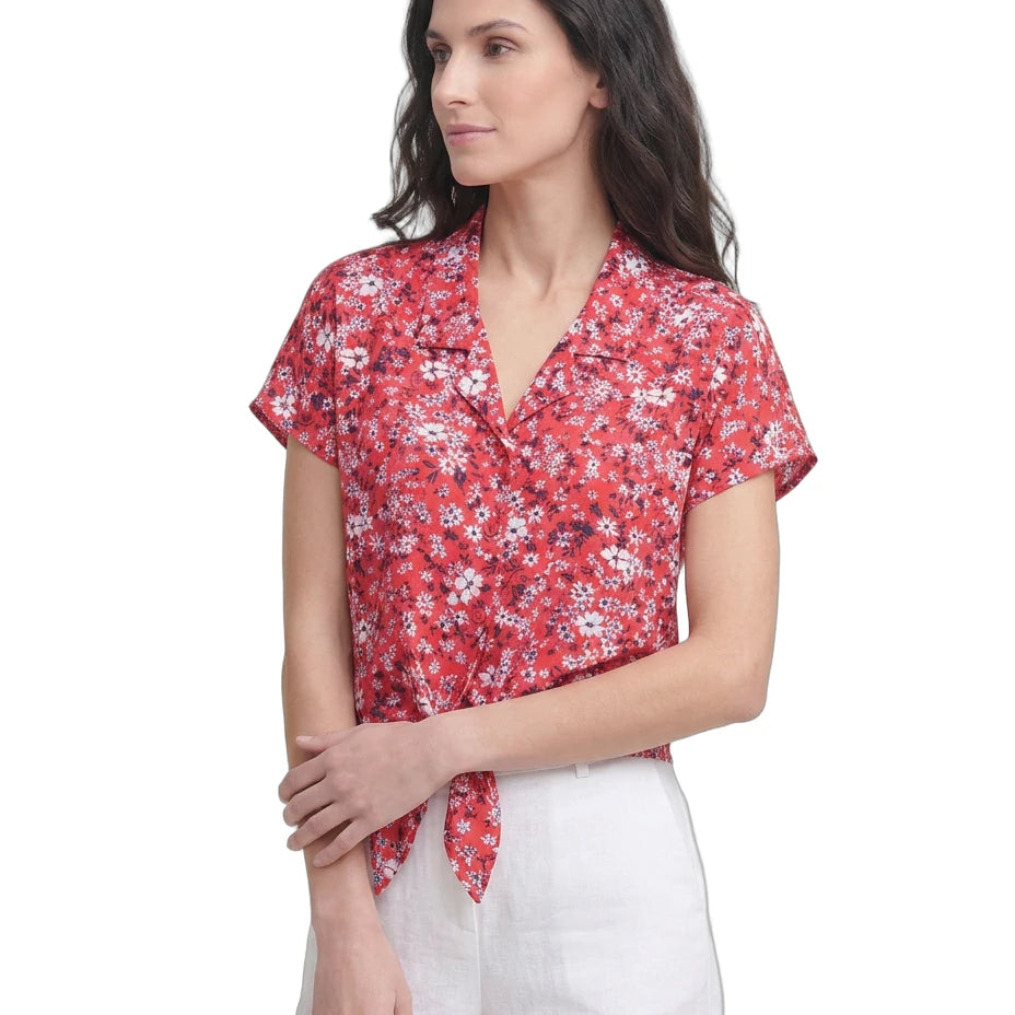 Woman wearing a red floral Calvin Klein blouse against a white background