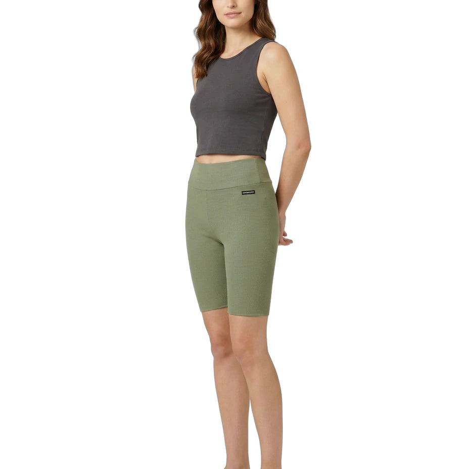 Woman wearing green athletic shorts and a gray tank top on a white background