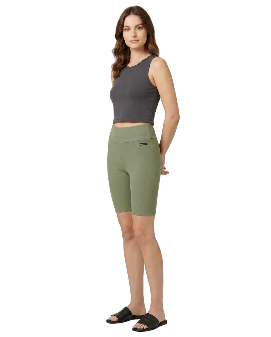 Woman wearing green athletic shorts and a gray tank top on a white background