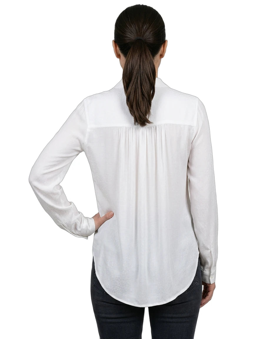 Woman wearing a white blouse with a subtle pattern on a white background